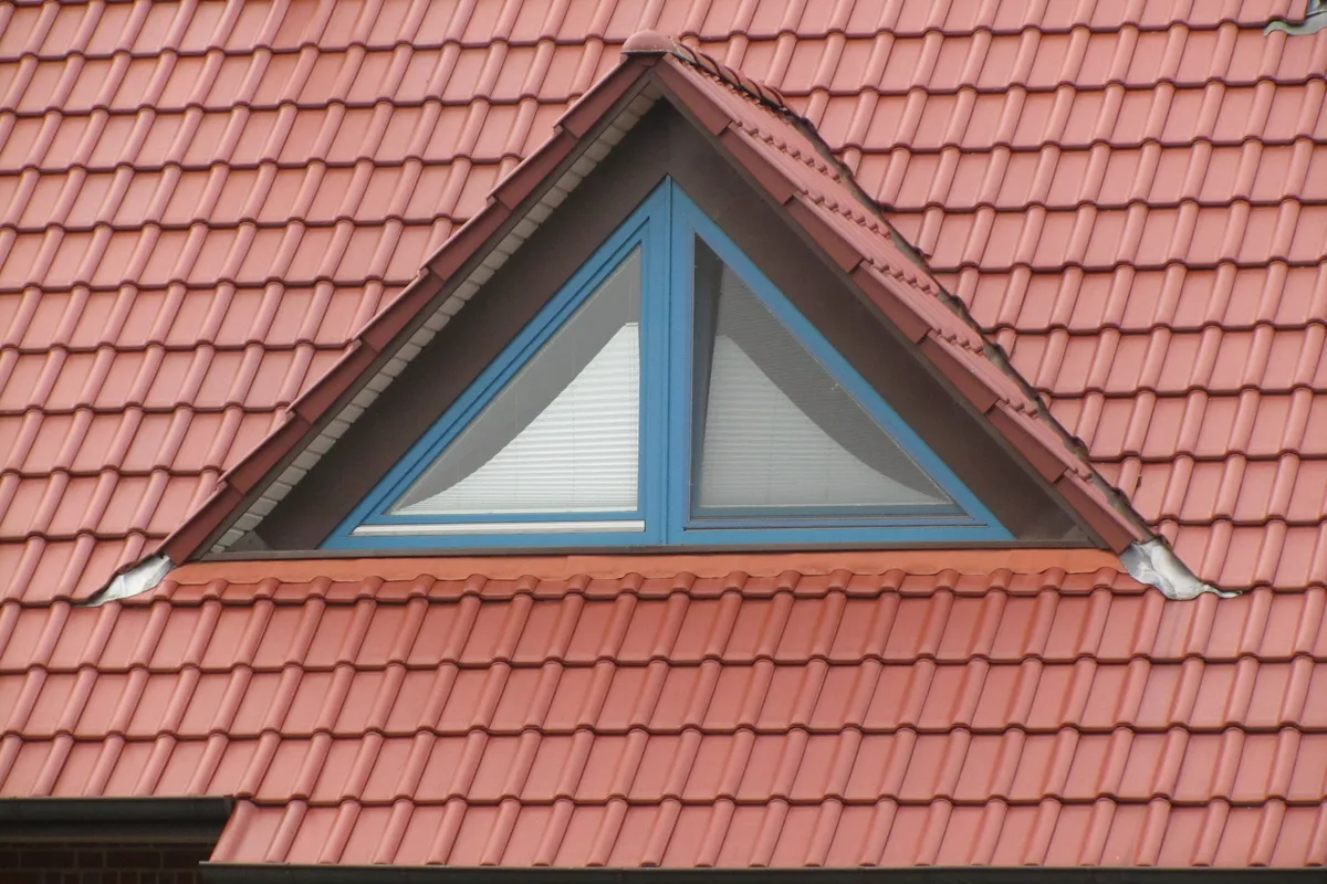 Lucarne triangulaire à deux vantaux, encastrée dans une toiture en tuiles